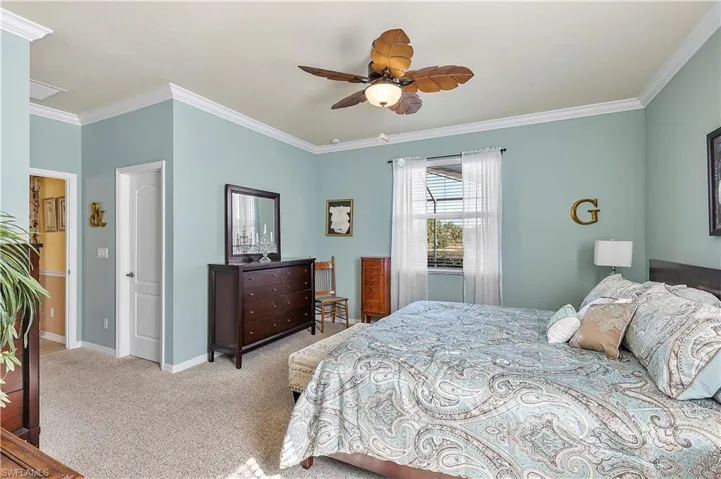 Carpeted bedroom with ceiling fan and crown molding