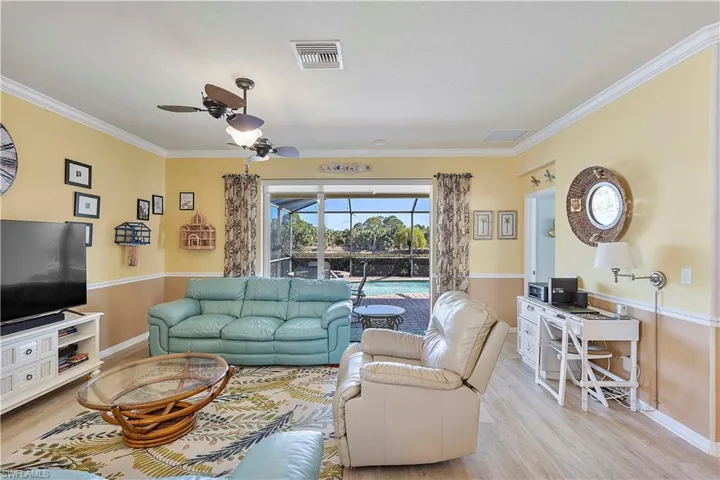 Living room with ceiling fan, crown molding, and light hardwood / wood-style floors