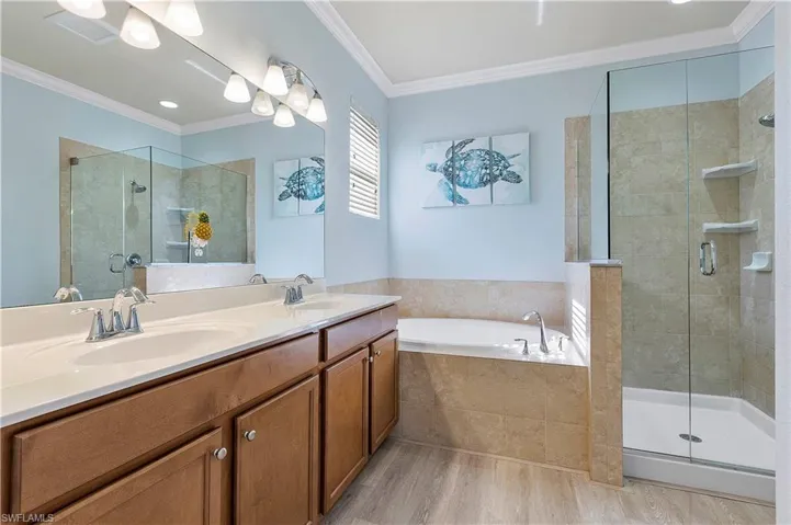 Bathroom featuring vanity, wood-type flooring, ornamental molding, and plus walk in shower