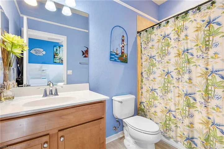 Bathroom featuring a shower with shower curtain, vanity, hardwood / wood-style flooring, and toilet
