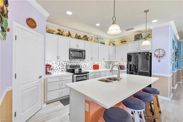 Kitchen with a kitchen island with sink, white cabinets, black fridge, sink, and stainless steel electric range oven