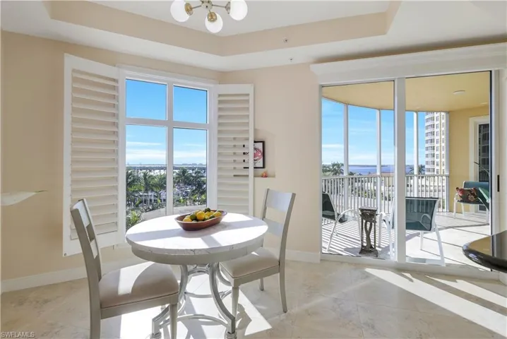 Dining room featuring a raised ceiling, a chandelier, and a healthy amount of sunlight