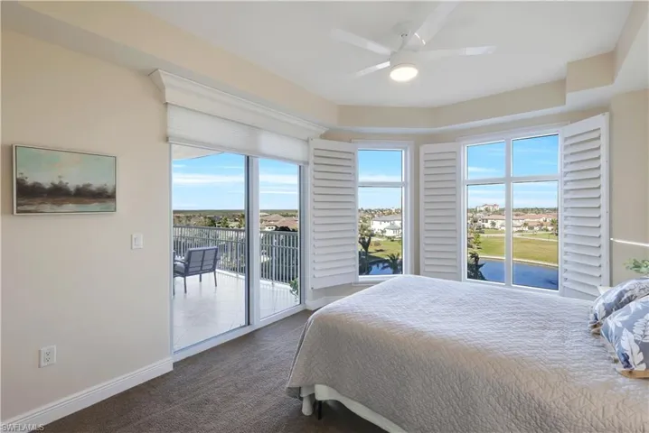 Bedroom featuring access to exterior, ceiling fan, and dark carpet
