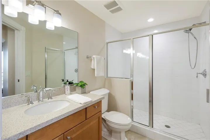 Bathroom featuring vanity, an enclosed shower, and toilet