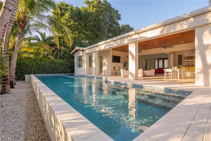 Elevated pool and integrated spa are surrounded by a generous pool deck and lush privacy landscaping, creating a secluded resort-style retreat