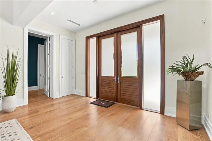 Elegant glass-paneled French doors welcome you home, complemented by custom electric screens that allow the covered front porch to be effortlessly enclosed