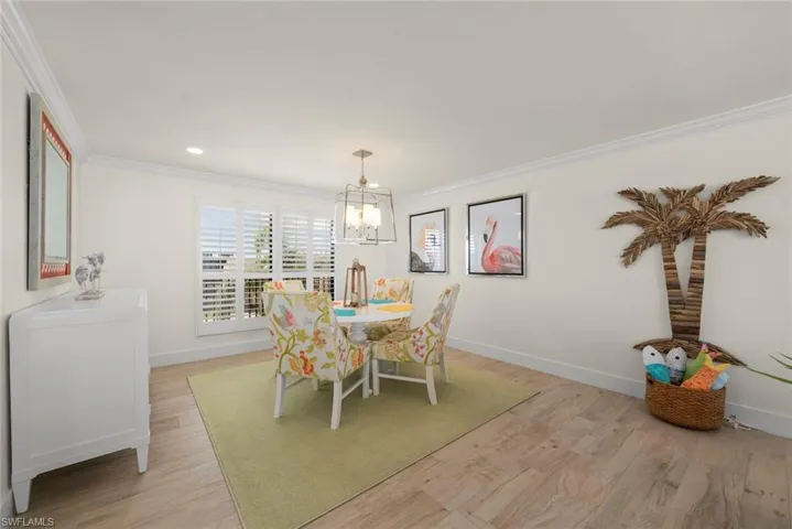 Light-filled room featuring wood-finish flooring, white crown molding, and plantation shutters