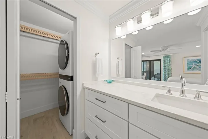 Bathroom vanity featuring white shaker cabinetry, an integrated rectangular sink, and a light-toned countertop. Full size w/d in closet