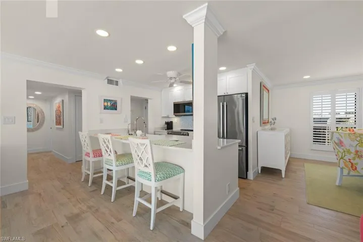 Kitchen featuring a breakfast bar with seating, white cabinetry, stainless steel refrigerator, and recessed lighting