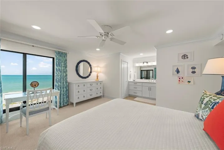 Expansive window framing ocean views, recessed lighting, crown molding, ceiling fan, and an integrated vanity area with double sinks