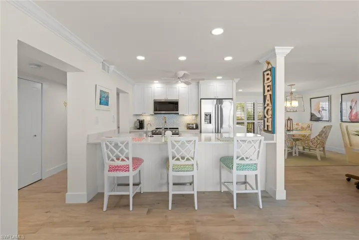 Kitchen featuring white cabinetry, stainless steel appliances, a breakfast bar, recessed lighting, and wood-finish flooring