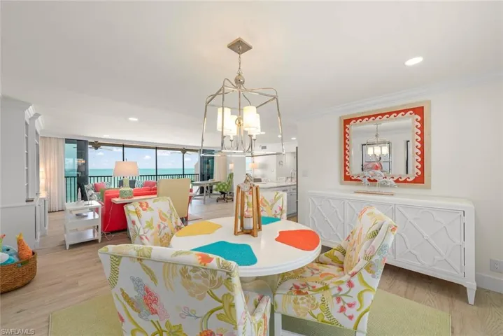 Spacious open-concept living area featuring wood-finish flooring, a contemporary chandelier, and a built-in sideboard with geometric detailing