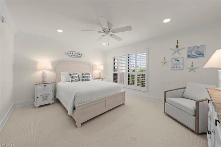 Spacious room featuring neutral carpeting, white plantation shutters, crown molding, and recessed lighting