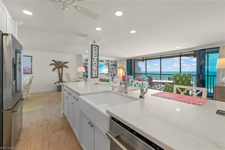 Kitchen featuring an oversized island with a farmhouse sink, stainless steel appliances, recessed lighting, and wood-finish flooring