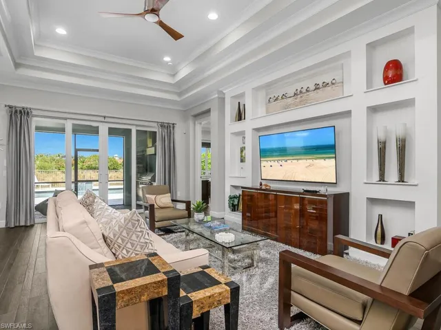 Living area featuring a ceiling fan, built in shelves, recessed lighting, french doors, and a raised ceiling