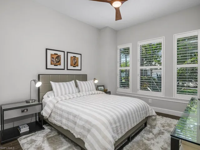 Bedroom with 3 big windows, ceiling fan, tile flooring.