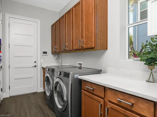 Laundry area featuring cabinet space, separate washer and dryer, dark wood finished floors, and baseboards