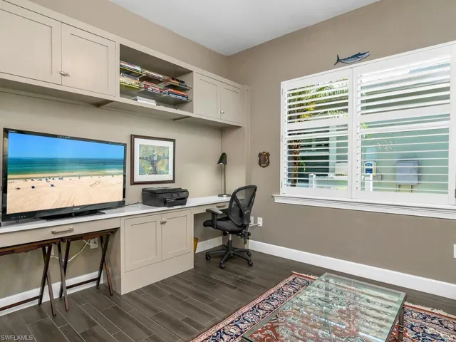 Office space featuring baseboards, dark wood-type flooring, and built in desk