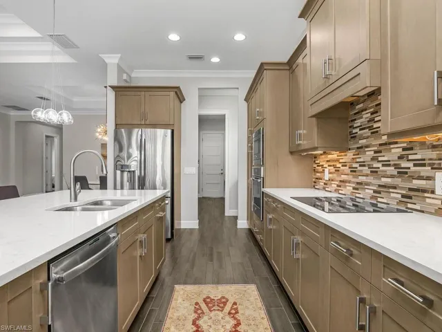 Kitchen with appliances with stainless steel finishes, a sink, ornamental molding, recessed lighting, and backsplash