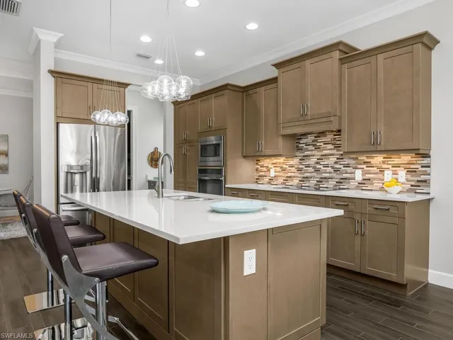 Kitchen featuring appliances with stainless steel finishes, a sink, crown molding, and decorative backsplash