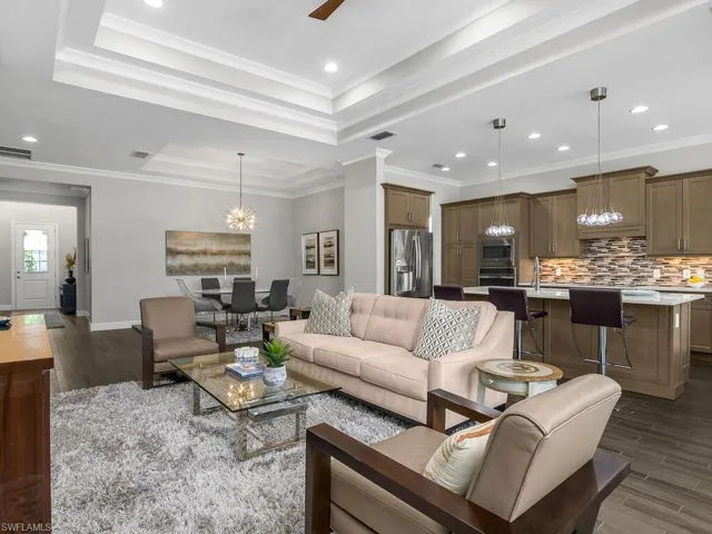 Living room with plank tile flooring, a raised ceiling, a chandelier, recessed lighting, and baseboards