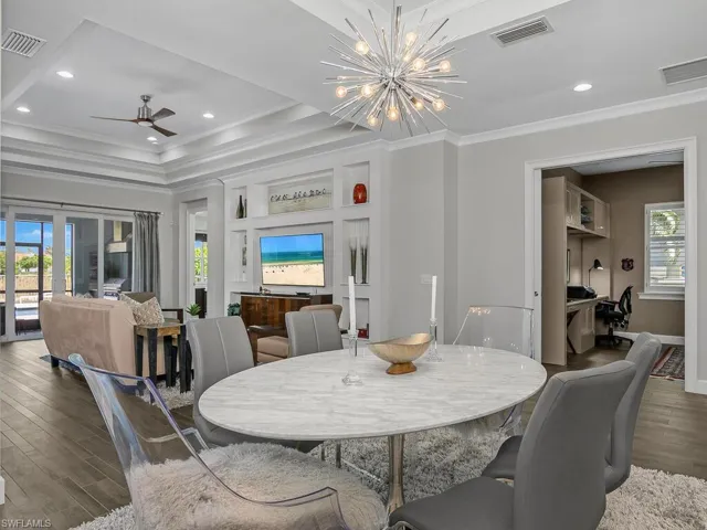 Dining room featuring wood finished floors, ornamental molding, a tray ceiling, ceiling fan, and baseboards