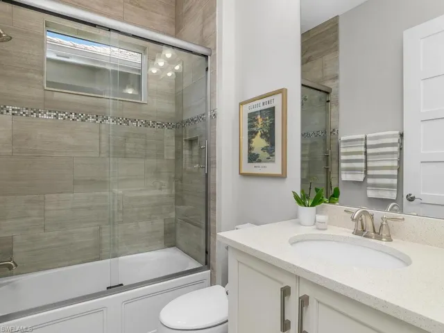 Full bath with vanity, toilet, and bath / shower combo with glass door