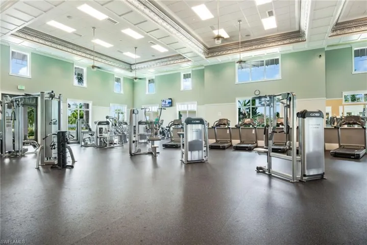 Workout area featuring a towering ceiling, healthy amount of natural light, and ceiling fan