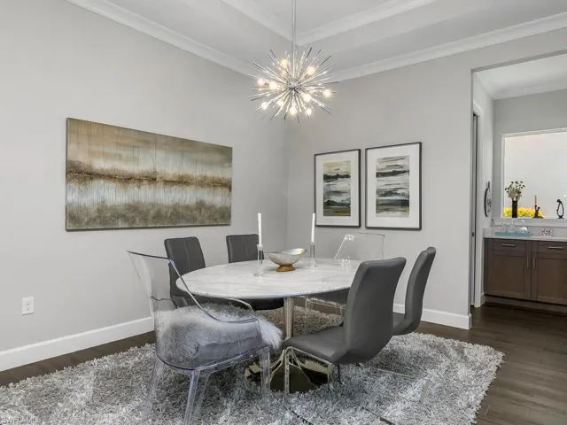 Dining room featuring dark wood-style flooring, a chandelier, baseboards, and ornamental molding
