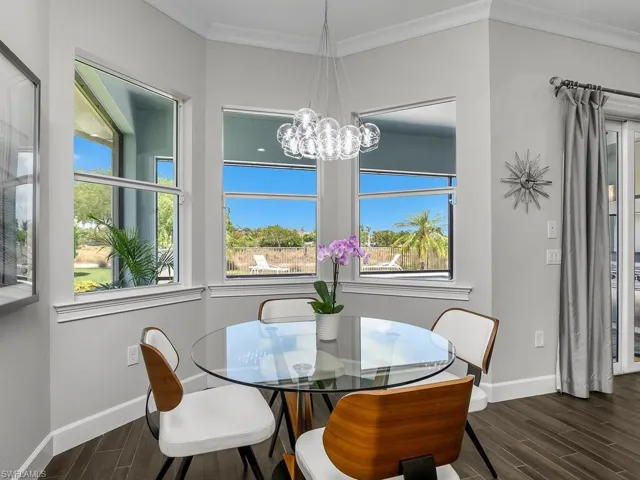 Dining area featuring wood tiled floors, baseboards, a chandelier, and ornamental molding