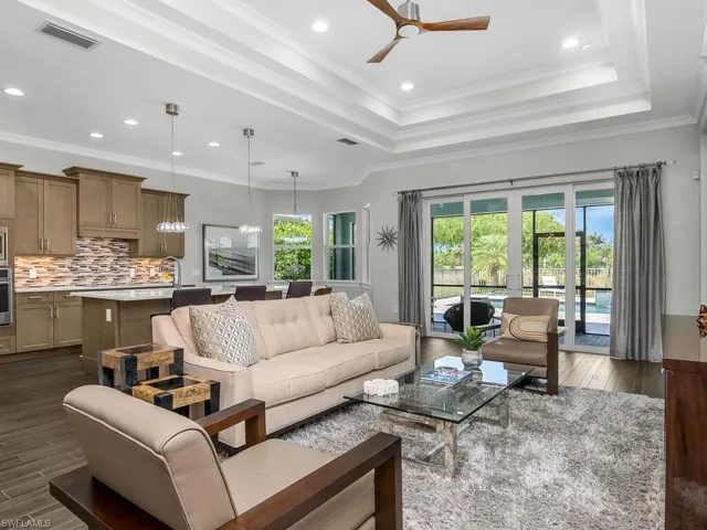 Living room with a ceiling fan, dark wood finished floors, recessed lighting, and a tray ceiling