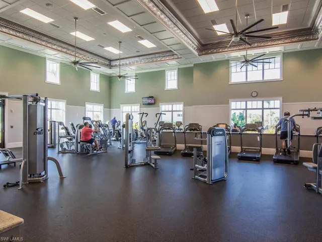 Gym with a ceiling fan, a towering ceiling, and a paneled ceiling