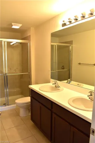 Bathroom featuring double vanity, a stall shower, and light tile patterned flooring