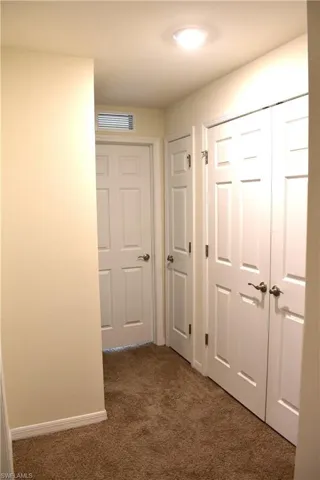 Corridor featuring dark colored carpet and baseboards