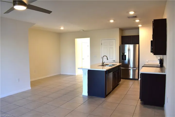 Kitchen with stainless steel appliances, ceiling fan, a center island with sink, light tile patterned floors, and recessed lighting