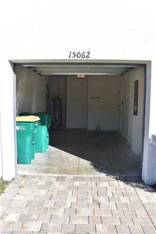 Garage with decorative driveway, electric water heater, and electric panel