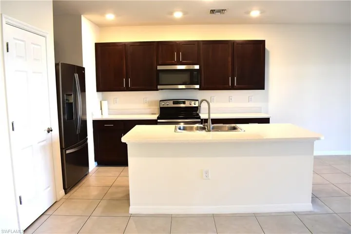 Kitchen featuring dark wood finish cabinetry, stainless steel appliances, and light countertops