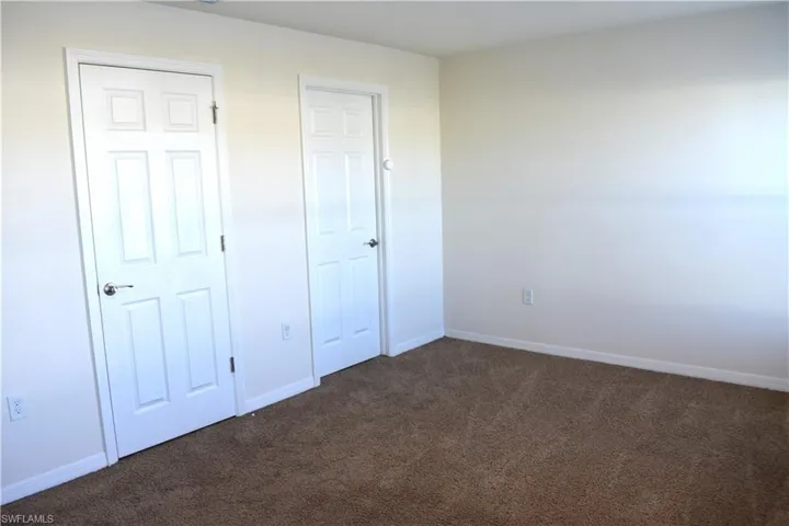 Unfurnished bedroom with baseboards and dark colored carpet