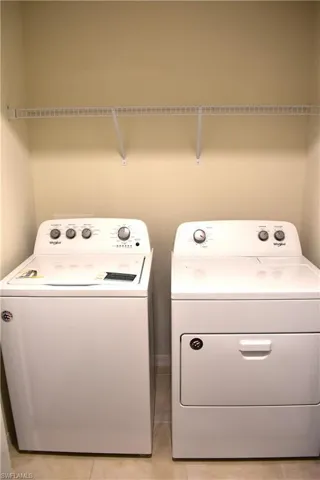 Laundry area with separate washer and dryer and light tile patterned floors