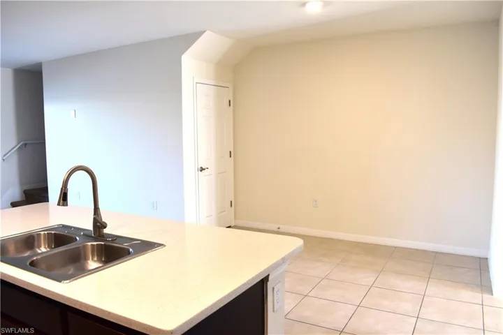 Kitchen with a center island with sink, light tile patterned floors, and light stone counters
