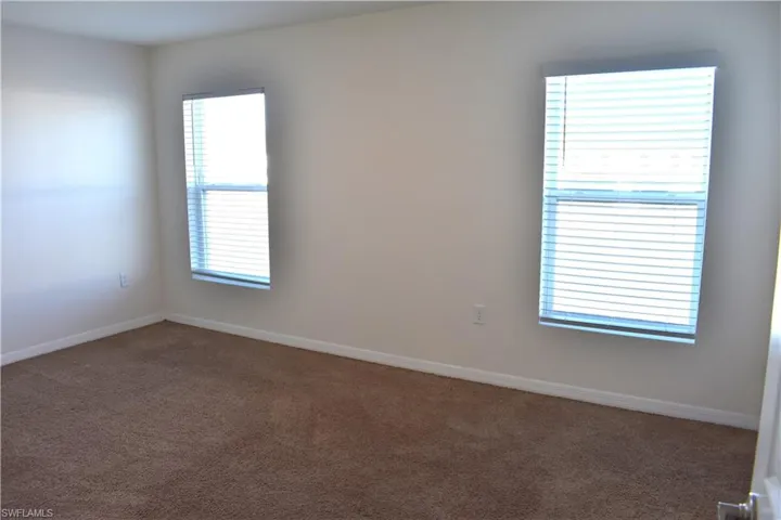 Unfurnished room featuring dark colored carpet and baseboards
