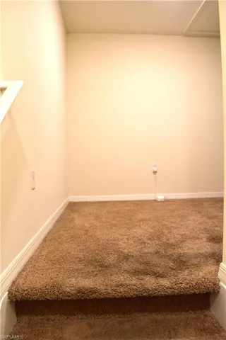Carpeted spare room featuring baseboards