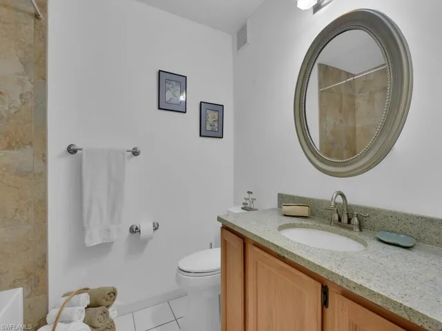 Bathroom with tile patterned floors, walk in shower, vanity, and toilet