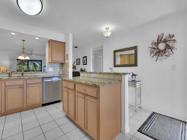 Kitchen with kitchen peninsula, sink, light tile patterned floors, pendant lighting, and dishwasher
