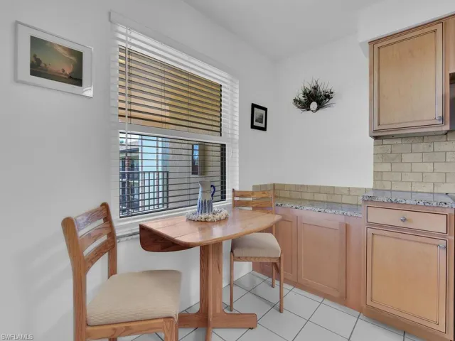 Kitchen with decorative backsplash, light tile patterned flooring, and light stone countertops