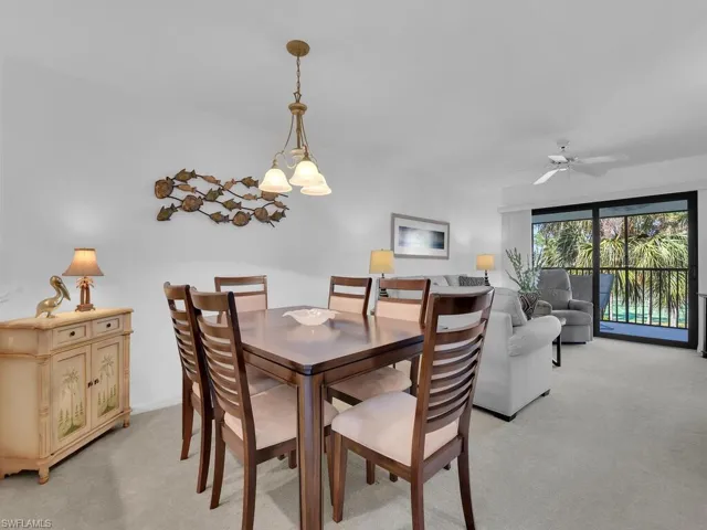 Dining area featuring light colored carpet and ceiling fan with notable chandelier
