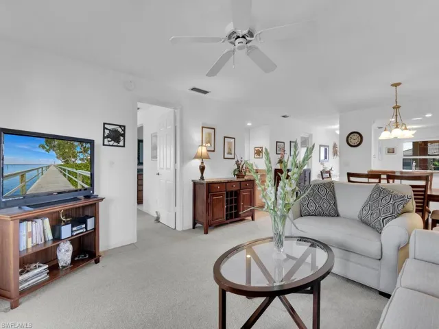 Carpeted living room with ceiling fan with notable chandelier