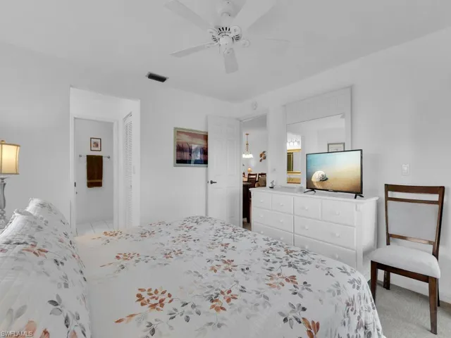 Bedroom featuring light carpet, ensuite bath, and ceiling fan