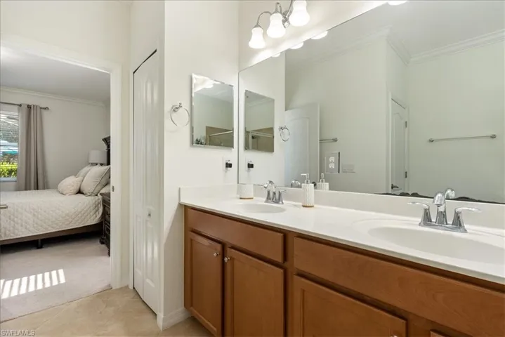 Bathroom featuring crown molding, double vanity, ensuite bathroom, and tile patterned floors