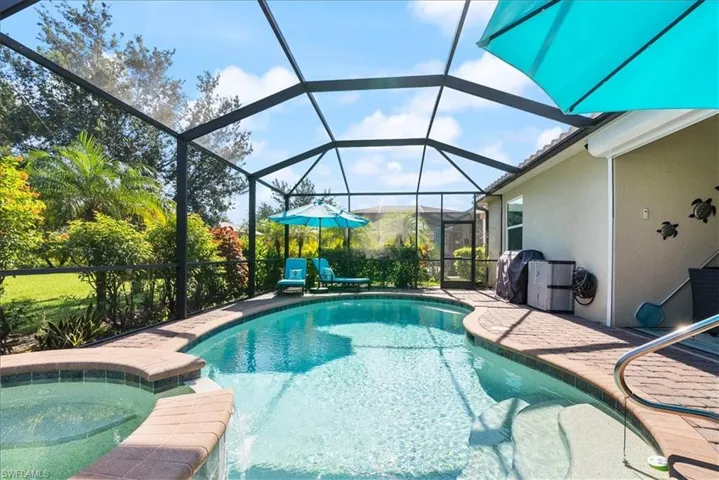 View of swimming pool with a pool with connected hot tub, area for grilling, a patio area, and a lanai